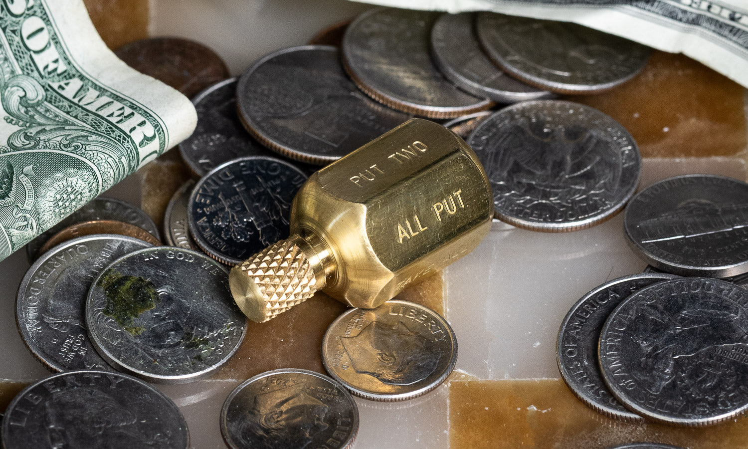 brass teetotum spinning top next to coins and dollar bills