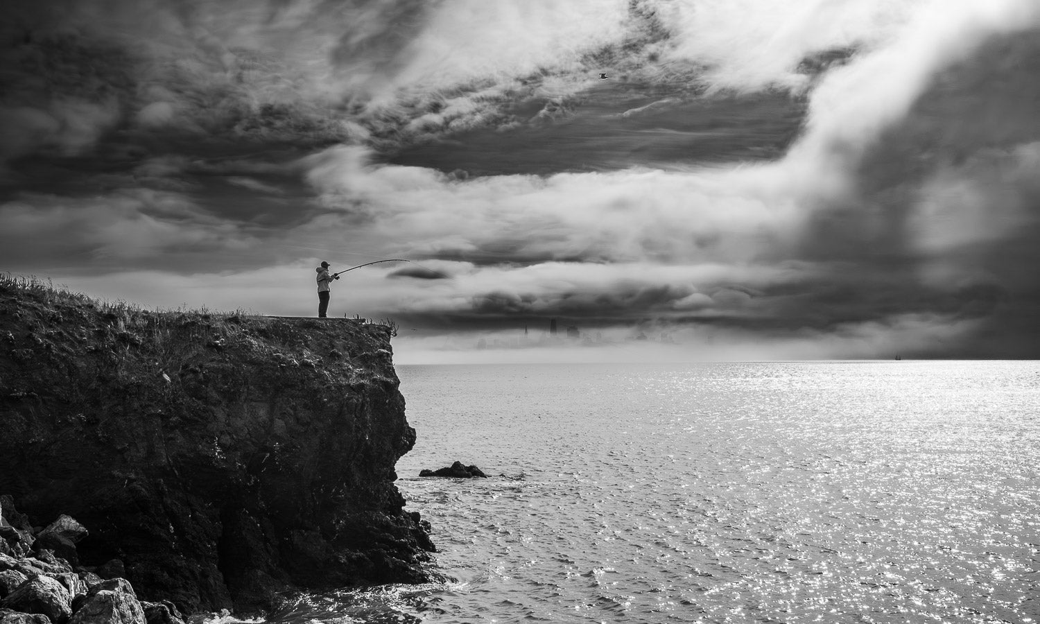 black and white image of a lone fisherman casting a line off the coast of San Francisco | Jeff Galfer Photography