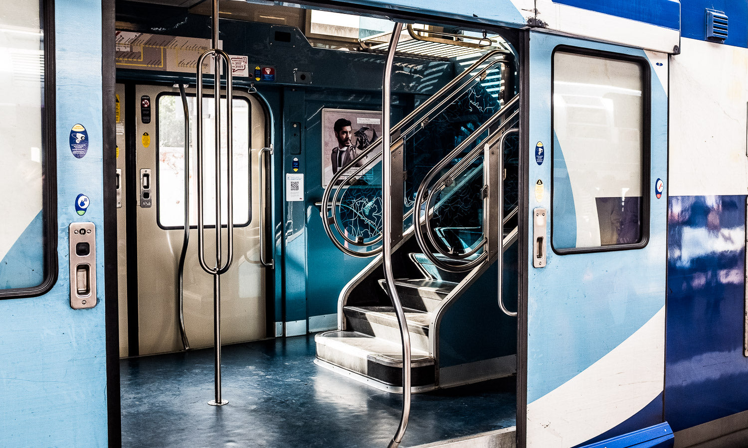 Blue and white train with open doors showing a staircase inside