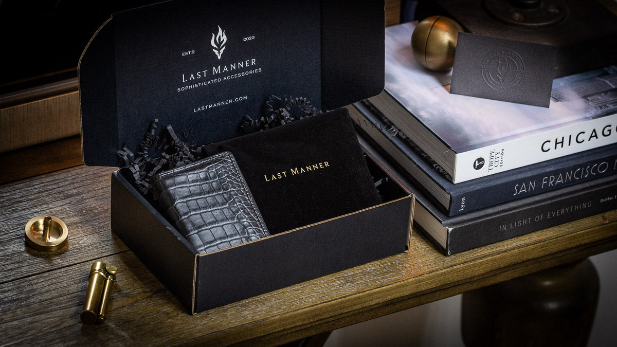 An alligator wallet packed in a Last Manner gift box next to a lighter and spinning top