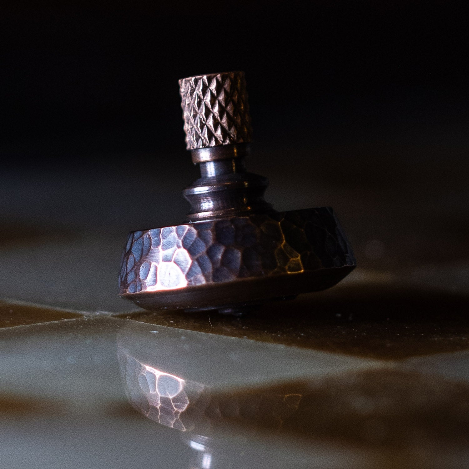 close up of knurling on a Fiddle Foundry spinning copper top with reflection | Last Manner
